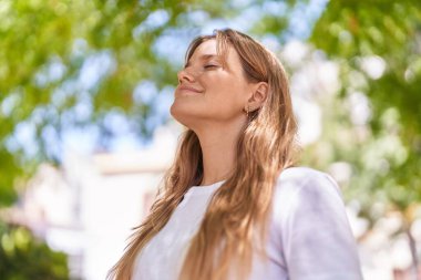 Young blonde girl smiling confident breathing at park