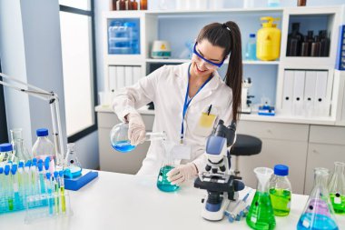 Genç ve güzel İspanyol bilim kadını laboratuarda test tüpüne sıvı döküyor.