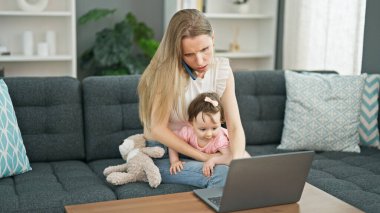 Anne ve kız kanepede oturup akıllı telefondan konuşuyorlar. Evde dizüstü bilgisayarla stres yapıyorlar.