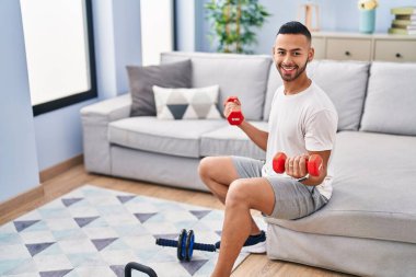 African american man smiling confident using dumbbells training at home