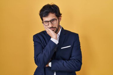 Sarı arka planda duran yakışıklı Latin adam çapraz kollu depresyon sorunlarından sıkılmış ve yorgun görünüyor.. 