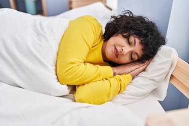 Genç, güzel, İspanyol bir kadın yatakta uzanıyor.