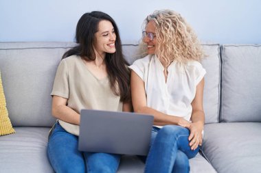 Evde dizüstü bilgisayar kullanan iki kadın anne ve kız.