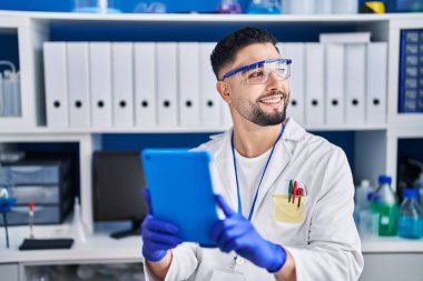 Genç Arap bilim adamı laboratuarda çalışan dokunmatik ped kullanıyor.