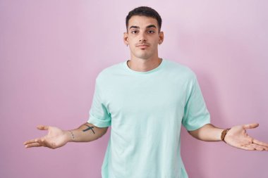 Pembe arka planda duran yakışıklı İspanyol adam habersiz ve kolları açık, hiçbir fikri yok.. 