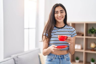 Genç İspanyol kız gülerek evde kahve içiyor.