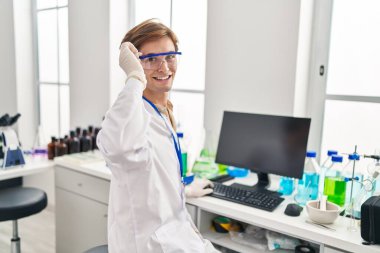 Young caucasian man scientist smiling confident using computer at laboratory