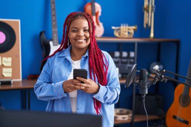 African american woman artist using smartphone at music studio