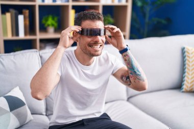 Evde sanal gerçeklik gözlüğü kullanarak video oyunu oynayan İspanyol genç adam.