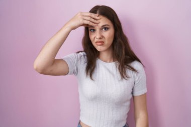 Pembe arka planda duran Latin kökenli genç kız. Alnındaki sorun yüzünden endişeli ve stresli. Kriz için endişeli. 