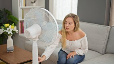 Kanepede oturan genç sarışın kadın sıcak bir başlangıç taraftarı yüzünden acı çekiyor.