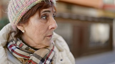 Ciddi bir suratı olan olgun İspanyol kadın sokağın kenarına bakıyor.