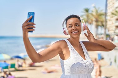 Afrika kökenli Amerikalı bir kadın deniz kenarında video araması yaptığından emin gülümsüyor.