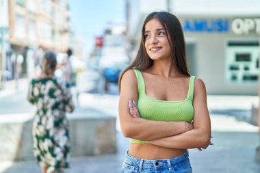 Sokakta kollarını kavuşturmuş genç, güzel İspanyol bir kadın.