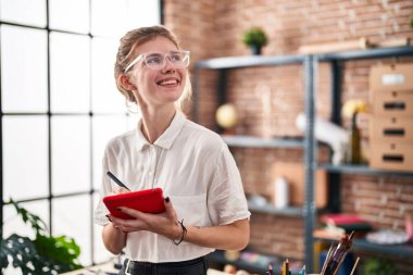 Young blonde woman artist smiling confident drawing on touchpad at art studio