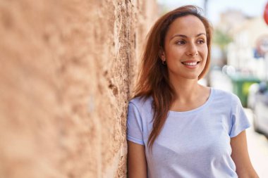 Gülümseyen genç bir kadın sokağın kenarına bakıyor kendinden emin.