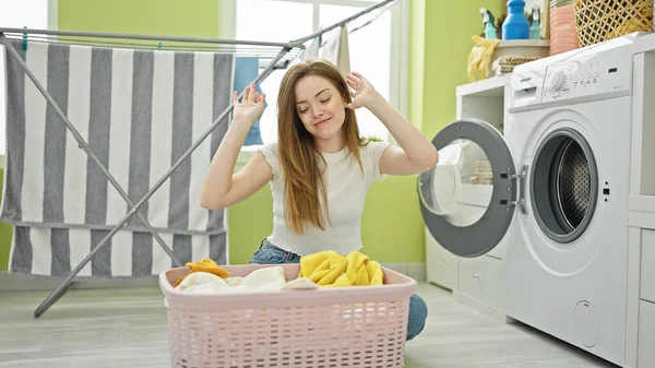 洗濯室で踊る服を洗っている若い金髪の女性 — ストック写真