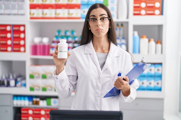 Mulher Morena Jovem Trabalhando Farmácia Farmácia Segurando Pílulas Deprimidas Preocupar — Fotografia de Stock