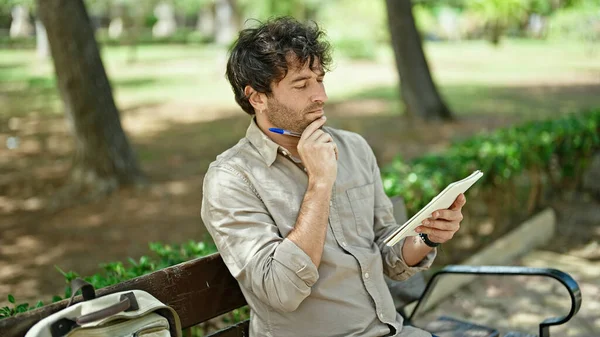公園でベンチ思考に座ってノートに書く若いヒスパニックの男 — ストック写真