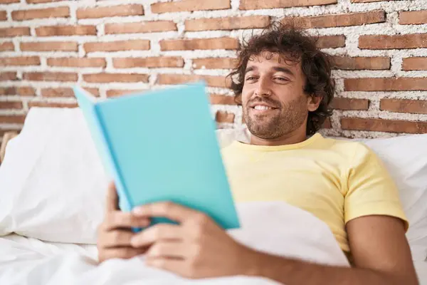 Young Hispanic Man Reading Book Lying Bed Bedroom — Fotografia de Stock