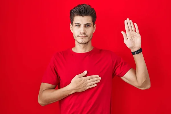 Ung Latinamerikansk Man Står Över Röd Bakgrund Svär Med Handen — Stockfoto