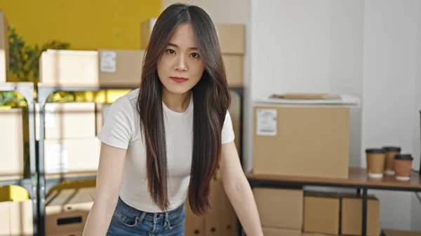 Young chinese woman ecommerce business worker standing with relaxed expression at office