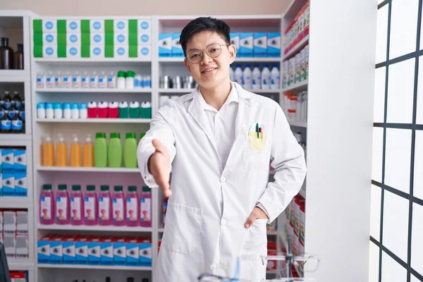 Young chinese man pharmacist smiling confident shake hand at pharmacy