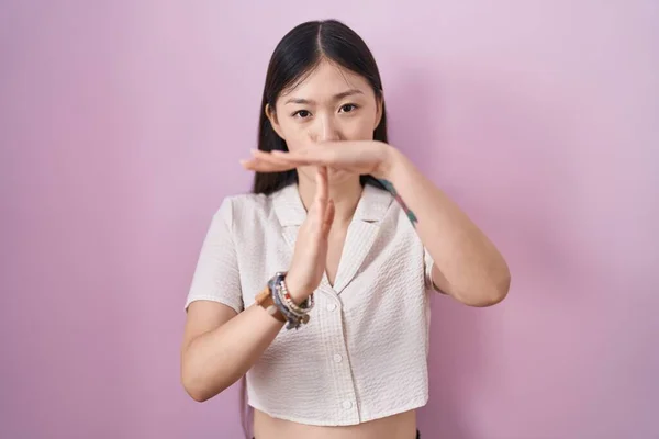 中国年轻女子站在粉红的背景上 用双手 沮丧和严肃的面孔做手势打发时间 — 图库照片