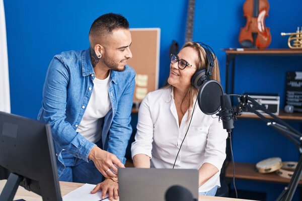 Man and woman musicians listening to music speaking at music studio