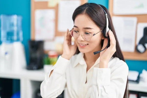 Young chinese woman call center agent smiling confident working at office