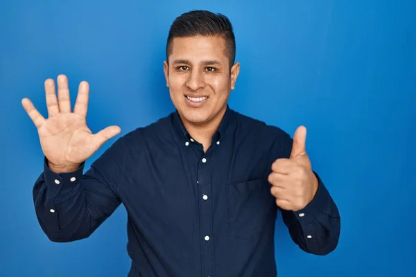 Jovem Hispânico Sobre Fundo Azul Mostrando Apontando Para Cima Com — Fotografia de Stock