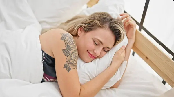 Young blonde woman lying on bed sleeping at bedroom