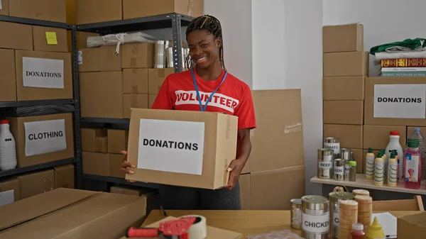 Africano Americano Mulher Voluntária Sorrindo Confiante Segurando Pacote Doações Escritório — Fotografia de Stock