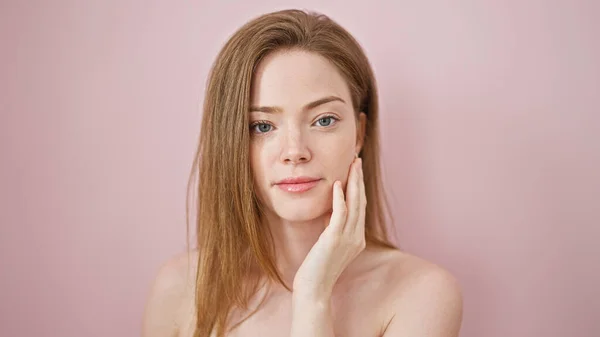 Ung Blond Kvinna Vidröra Ansiktet Med Handen Över Isolerad Rosa — Stockfoto