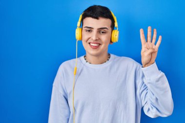 İkili olmayan kişi kulaklık kullanarak müzik dinlerken dört numaralı parmaklarıyla gülümseyerek kendinden emin ve mutlu görünüyor.. 