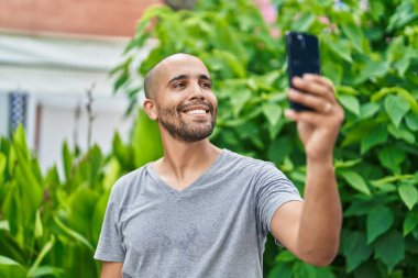 Young latin man smiling confident making selfie by the smartphone at park