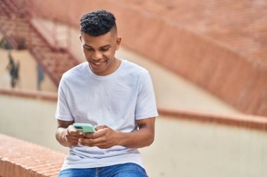 Sokakta akıllı telefon kullanan, kendine güvenen genç Latin adam.