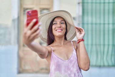 Genç ve güzel İspanyol kadın turist gülümsüyor. Kendine güveni tam. Sokakta akıllı telefondan selfie çekiyor.