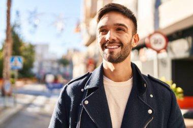 Young hispanic man smiling confident looking to the side at street