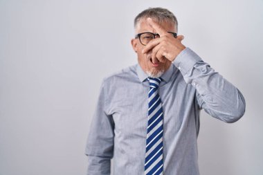 İspanyol iş adamı, gri saçlı, gözlüklü, şok içinde yüzünü ve gözlerini kapayarak utangaç ifadesiyle parmaklarının arasından bakıyor.. 