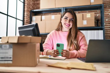 Genç, güzel, İspanyol bir kadın. İş kadını. Ofiste akıllı telefon kullanıyor.
