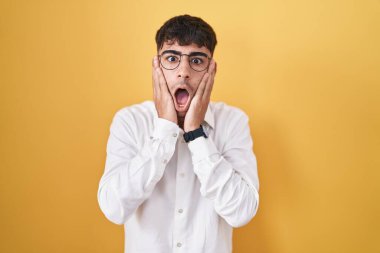 Sarı arka planda duran İspanyol genç adam korkmuş ve şok olmuş, şaşırmış ve şaşırmış bir yüz ifadesi var. 