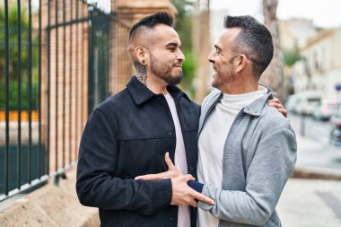 Two men couple smiling confident hugging each other at street