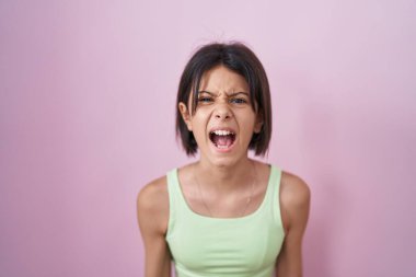 Pembe arka planda duran genç kız kızgın ve kızgın çığlık atıyor sinirli ve öfkeli, öfkeyle bağırıyor. öfke ve agresif konsept. 