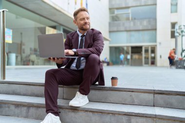 Middle age man business worker smiling confident using laptop at street