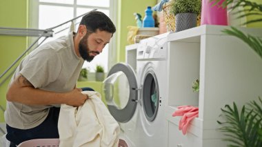 Çamaşırhanede çamaşır yıkayan İspanyol genç adam.