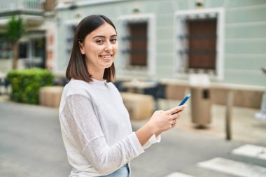 Sokakta akıllı telefon kullanan, kendine güvenen genç İspanyol kadın.