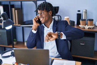 Afrikalı Amerikalı iş adamı akıllı telefondan konuşuyor. Ofiste nöbet tutuyor.