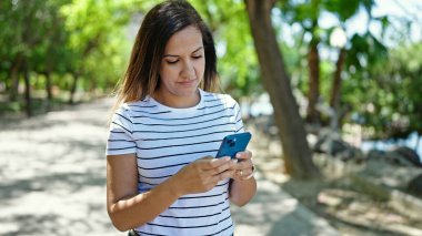Ortadoğulu kadın parkta akıllı telefon kullanıyor.