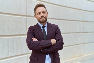 Middle age man business worker standing with arms crossed gesture at street